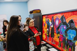 Deux personnes admirent l'oeuvre collective en mosaïque exposée à la bubliothèque