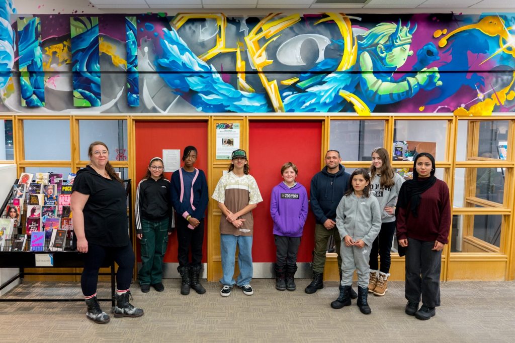 Les jeunes du Centre de services scolaires Marie-Victorin devant la murale réalisée par l’artiste Korb, inspiré de leurs idées – Photo : Jean-Michael Seminaro