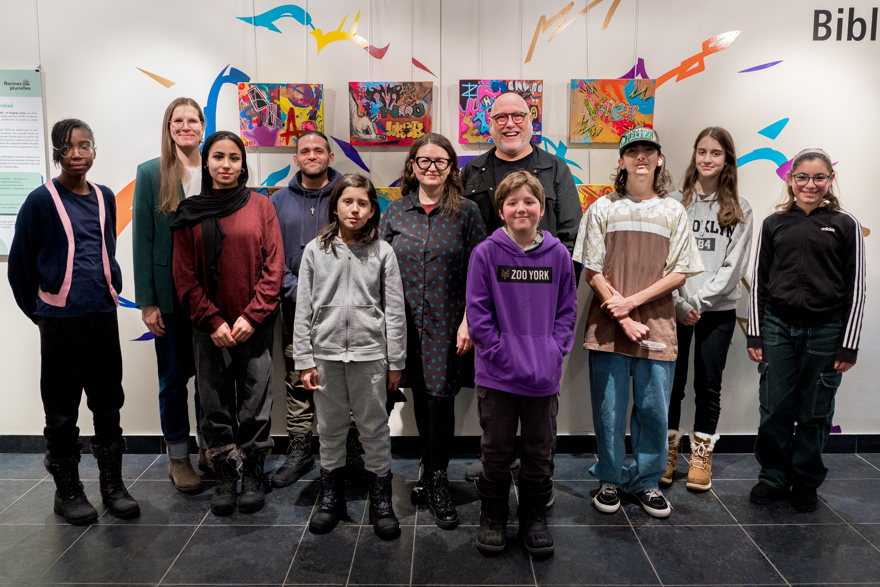 Marie-Hélène Mathieu (médiatrice interculturelle au Centre de services scolaire Marie-Victorin), Jonathan Barbier alias Korb (artiste), Dominique Malenfant-Gamache (cheffe de division arts et patrimoine, Bureau de la culture et des bibliothèques, Ville de Longueuil) et Michel Vallée (président-directeur général, Culture pour tous) entourés des jeunes participants aux ateliers de Racines plurielles – Photo : Jean-Michael Seminaro